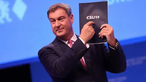 EPA Bavarian Premier Markus Söder points at a party programme at his Christian Social Union (CSU) party conference