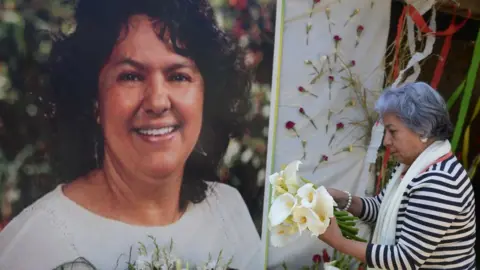 AFP VIA GETTY IMAGES The president of the NGO Committee of Relatives of the Disappeared in Honduras, Bertha Oliva, lays a wreath on an alter in memory of murdered indigenous Honduran environmentalist Berta Caceres
