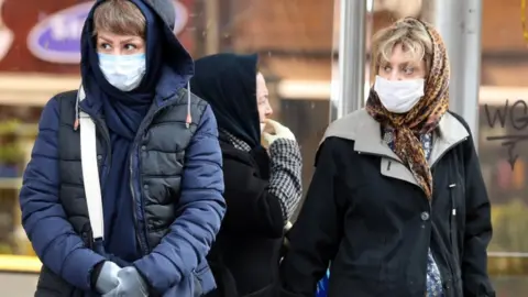 EPA Iranians wearing face masks walk past in a street of Tehran, Iran, on 26 February 2020