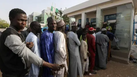 Reuters People queue to withdraw cash from an automated teller machine (ATM) at a bank, ahead of presidential elections, in Zamfara, Nigeria February 8