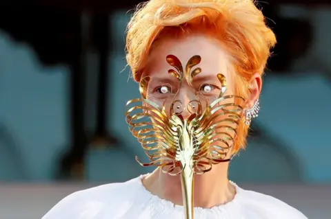 Yara Nardi / Reuters Actor Tilda Swinton hides behind a gold mask