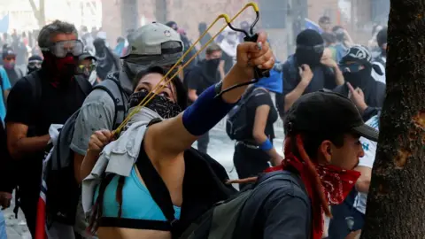 Reuters A woman holds a slingshot during a protest