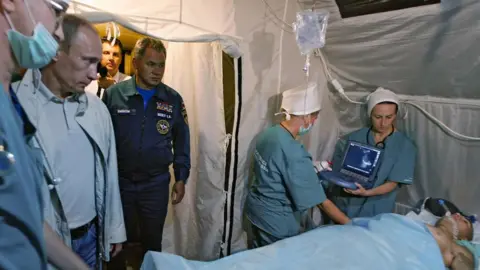 Getty Images Vladimir Putin (2nd L) looks at a man injured during fighting in South Ossetia during a visit to a field hospital in Vladikavkaz, the provincial capital of the region of North Ossetia