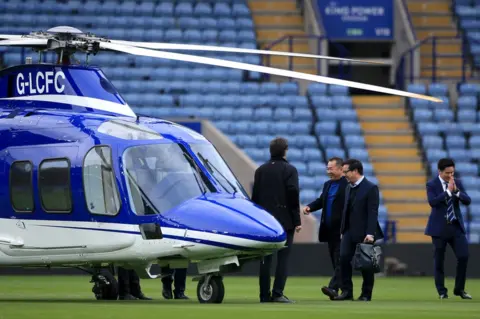 PA Media Vichai Srivaddhanaprabha (second left) and vice chairman Khun Aiyawatt "Top" Srivaddhanaprabha (second right) leave the ground in a helicopter after the final whistle in the Barclays Premier League match at the King Power Stadium, Leicester.. 03/04/2016