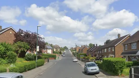 A residential street with cars parked on the side of the road