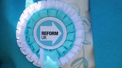 Reform UK rosette pinned to a campaigner 