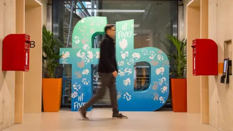 PA A man walks past a Facebook logo at Facebook's new Frank Gehry-designed headquarters at Rathbone Place in London.