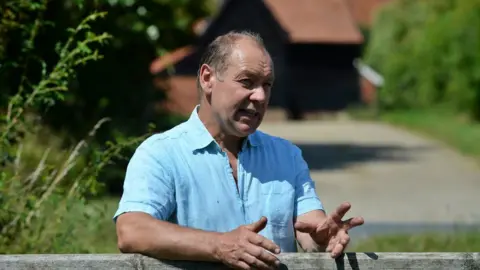 NFU Man with short dark hair leaning on farm gate