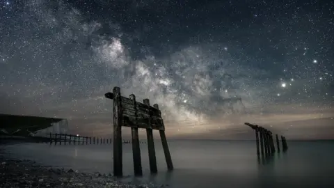 Giles Embleton-Smith/SDNPA The Milky Way is shown in a night sky with the Seven Sisters cliffs in the background, the sea and stony beach in the foreground