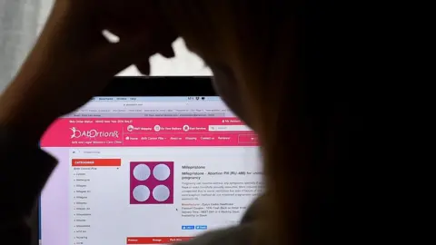 Getty Images A person looks at a mifepristone abortion pill for unintended pregnancy on a computer