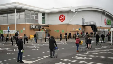 AFP People queue for supermarket while social distancing