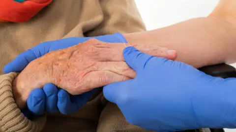 Getty Images Carer with gloves on