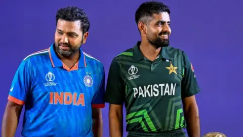 Getty Images India's captain Rohit Sharma (L) and his Pakistani counterpart Babar Azam stand beside the tournament trophy as they attend the Captains' Day event, an interaction session between the captains of all participating teams and the media at the Narendra Modi Stadium in Ahmedabad on October 4, 2023, on the eve of the the 2023 ICC men's cricket World Cup one-day international (ODI) match between England and New Zealand. (Photo by Punit PARANJPE / AFP) (Photo by PUNIT PARANJPE/AFP via Getty Images)
