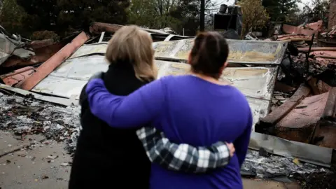 Reuters Residents comfort each other as they look at the remains of their homes in Paradise on 22 November 2018