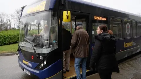 Shaun Whitmore Passengers board a bus