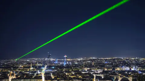 Getty Images A bright green laser beam shining in the night sky above Lyon, France