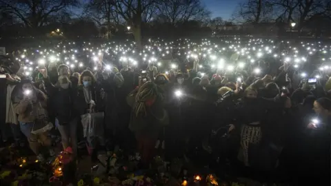 PA Media Hundreds turn on their phone torches at the bandstand in Clapham Common