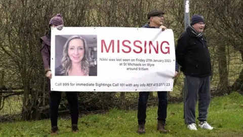 PA Media Members of the public line the road into St Michael"s on Wyre, Lancashire, with missing posters of Nicola Bulley