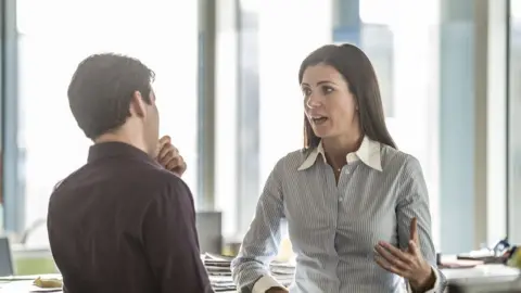 Getty Images Man and woman talking in an office