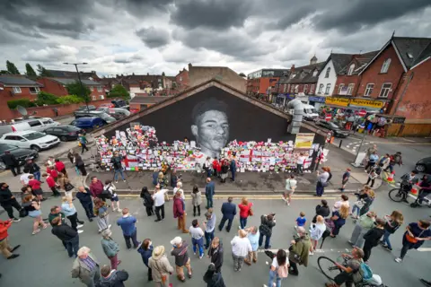 Christopher Furlong / Getty Images People look at the messages of support and the newly repaired mural of England footballer Marcus Rashford by the artist known as AKSE_P19 in Manchester, England