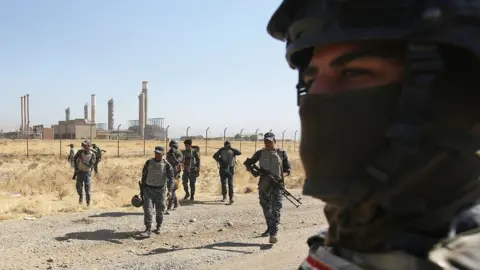 AFP Iraqi forces walk in front of an oil production plant as they head towards the city of Kirkuk during an operation against Kurdish fighters on October 16, 2017