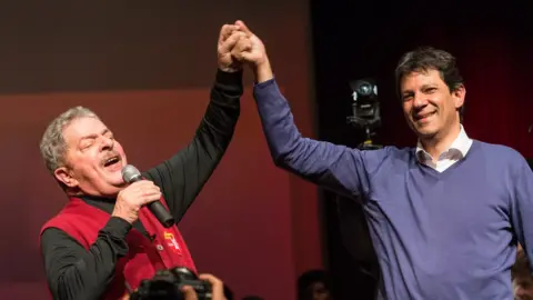 Getty Images Luiz Inacio Lula da Silva (left) raises the hand of Fernando Haddad during a campaign rally in 2012