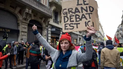 Getty Images A Yellow Vest protester in Toulouse with a phrygian cap holds a placard reading 'The big debate is here' - 26 Jan 2019