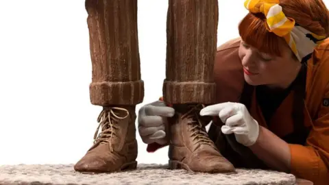 Warner Bros Pictures Jen Lindsey-Clark fixing the chocolate sculpture's boot