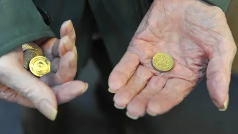 BBC Elderly person's hands holding coins