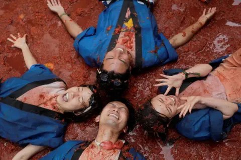 Eva Manez / Reuters Revellers play in tomato pulp at La Tomatina food fight festival
