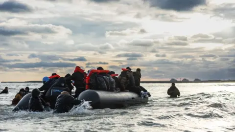 Getty Images Migrants board a smuggler's boat in an attempt to cross the English Channel, on the beach of Gravelines, near Dunkirk, northern France on April 26, 2024