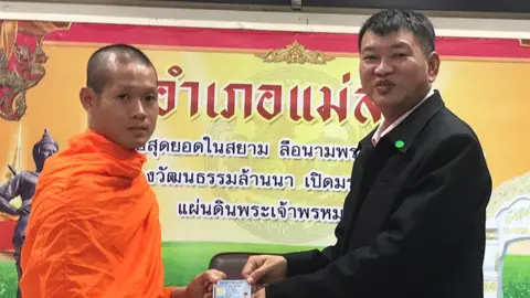 EPA Wild Boar soccer team coach-turned-Buddhist monk Ekapol Chantawong (L) as he receives Thai citizen ID card from Mae Sai District Chief Somsak Kanakham (R)