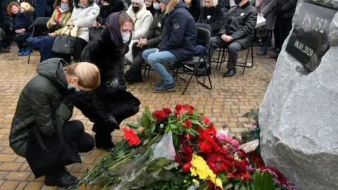 Getty Images Women lay flowers at a memorial ceremony for victims of the Ukraine air crash (08/01/21)