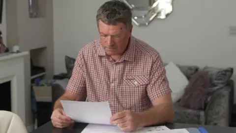 Stephen Clee at a table looking down at paperwork