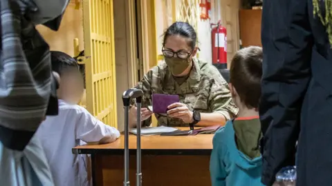 Afghan nationals receive visas from a member of the UK armed forces