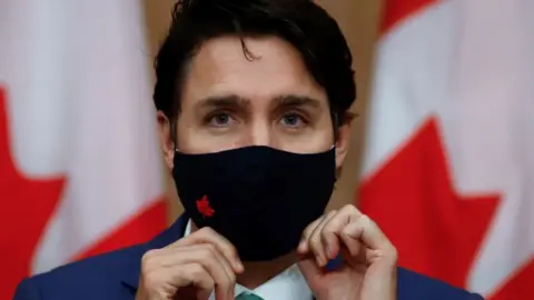 Reuters Canadian Prime Minister Justin Trudeau puts on a mask at a news conference held to discuss the country's coronavirus disease