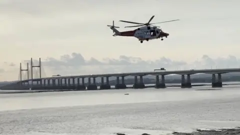 EPA A helicopter hovering over the Severn Estuary with the Prince of Wales Bridge in the background