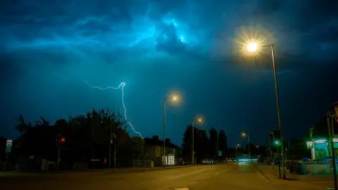 John E. Walsh / Twitter @akazeeox A lightning bolt and bright blue sky in Cambridge