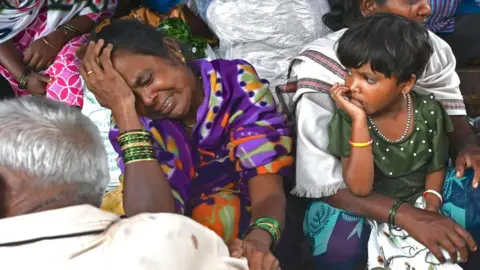 Getty Images Relatives of the people who lost their lives in a landslide, weep in a house at Irshalwadi village in Raigad district of India's Maharashtra state on July 20, 2023.