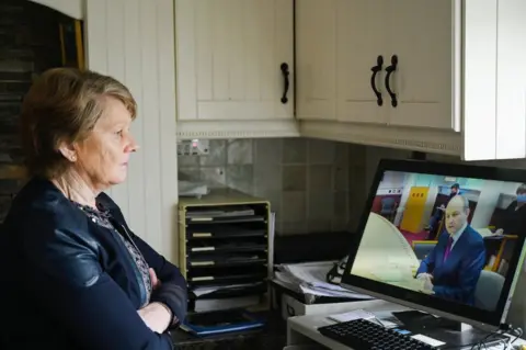 Reuters Catherine Corless watches an online briefing from the taoiseach for survivors of the homes