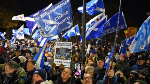 Getty Images Pro-Scottish independence supporters wave Saltire flags during a rally outside parliament in Edinburgh on November 23, 2022