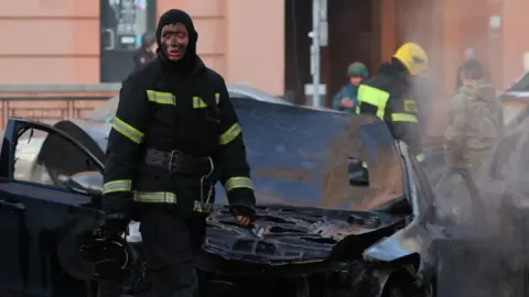 Reuters A firefighter takes a pause as he works to extinguish burning cars following what Russian authorities say was a Ukrainian military strike in Belgorod, Russia December 30, 2023