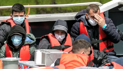 Getty Images People in lifejackets and face masks arrive ashore in Dover