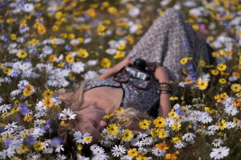 Tommy Trenchard A woman lying on the ground among flowers