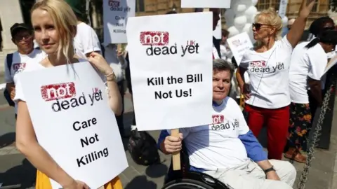 Reuters Campaigner holding placard saying Care Not Killing