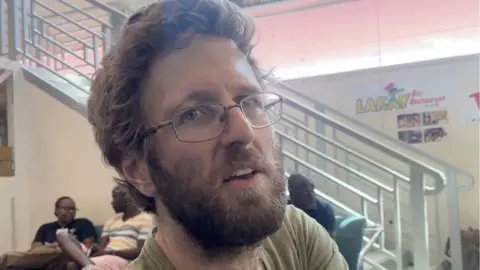 Brian Kontz, a man with ginger hair, a beard and glasses, speaks.