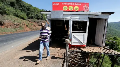 Reuters Harun Karanja, the owner of Facebook Curio Shop, uses his mobile phone to access his Facebook account near the Rift Valley town of Mai Mahiu, Kenya March 28, 2018.