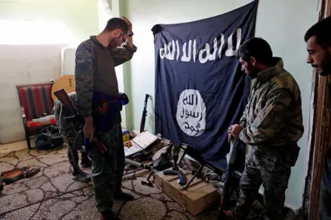 Reuters SDF fighters with a captured IS fag