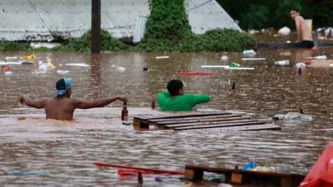 People wade through flooded streets in Encantado, Rio Grande do Sul state, southern Brazil. Photo: 2 May 2024