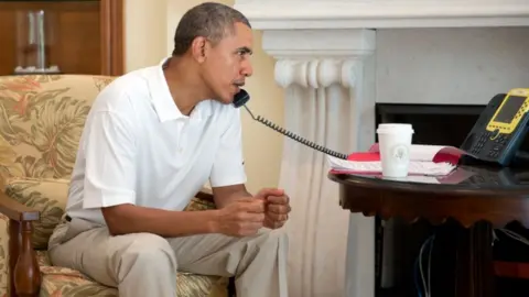 White House Handout Barack Obama pictured sitting down while on the telephone (file picture)